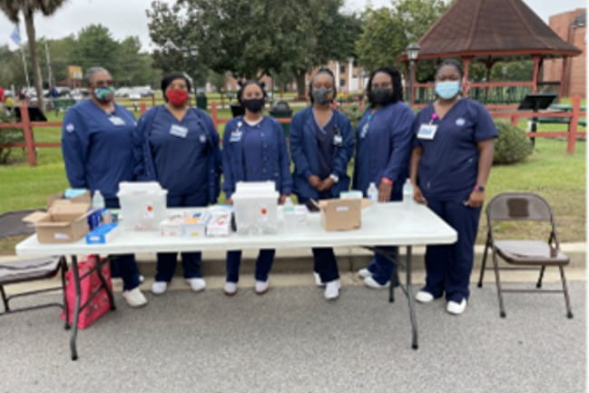 A group of people standing around a table outside